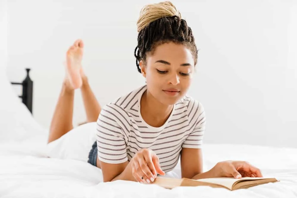 African female reading a book on how to install sisterlocks without formal training on her specific hair texture.