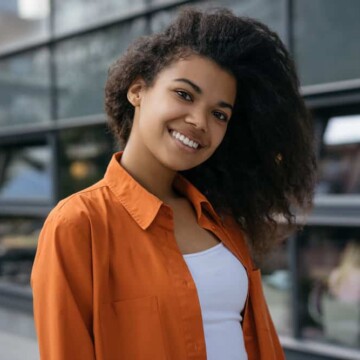 A cute black girl with a curly and textured hair texture that's moisturized after sleeping on a satin pillowcase.