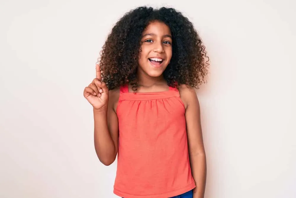 A young African American female wearing a curly hairstyle that's perfect for a special occasion or formal affair.