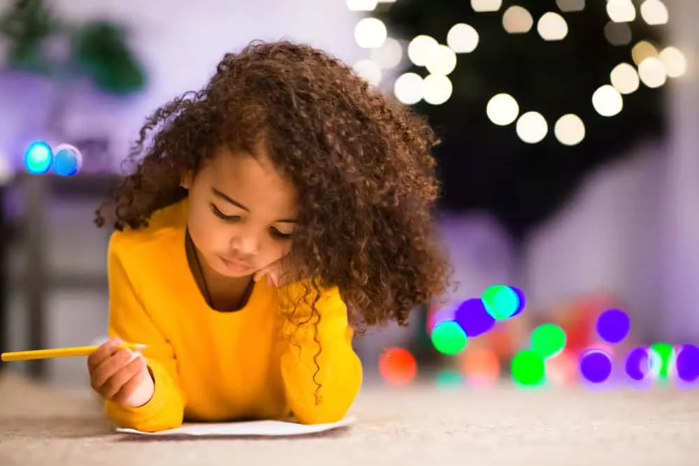 An endearing African American toddler with curly long hair styled with hair ties and a gorgeous bow.