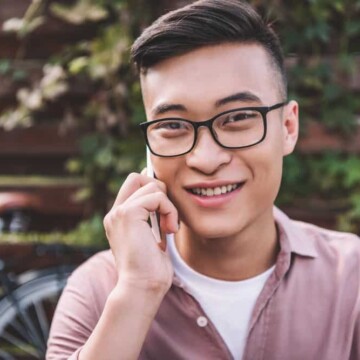 An Asian male with a dark brown hair color is wearing a parted two-block haircut with a type 1 defined hair texture.