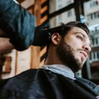 A white male with choppy hair is getting a mid-fade Edgar haircut resembling the baseball player Edgar Martinez.