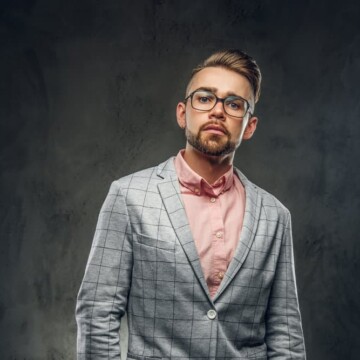 A stylish male wearing a classic french crop with a taper fade that requires minimal styling on his short hair.