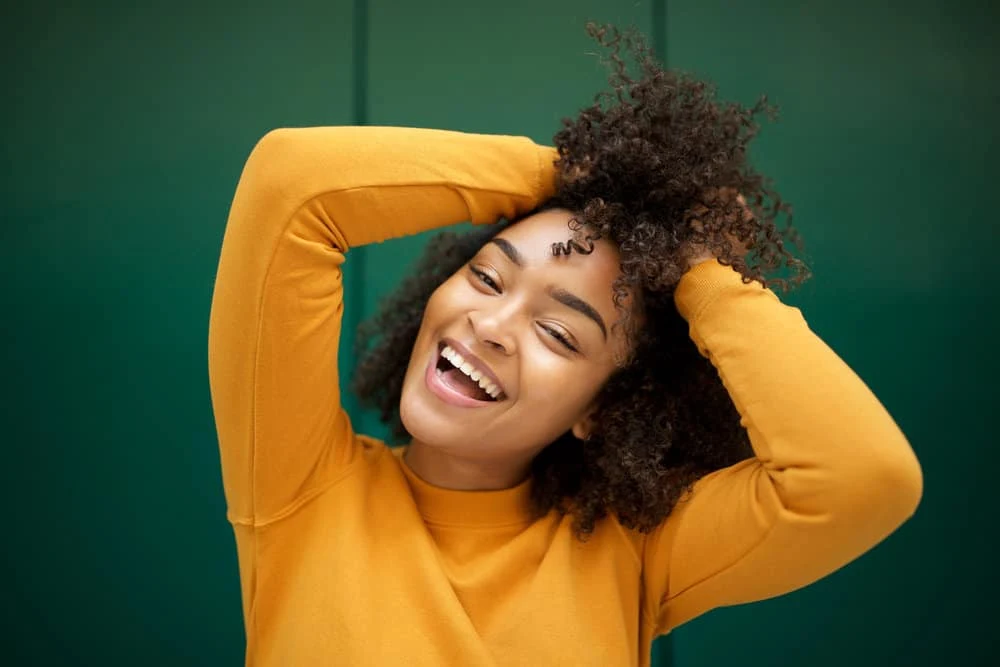 A black girl with textured hair styled with hair oils, like castor oil, jojoba oil (a carrier oil), and resin tree sap.