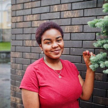 A black female with a 4C kinky hair texture wearing very short hair that highlights natural curls and coily hair strands.