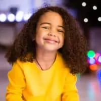 A cute toddler girl's hair is worn in a loose shoulder-length hairstyle after removing a curly fishtail braid.