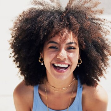 A beautiful black woman with dry and brittle hair after using too much protein on her naturally wavy hair.