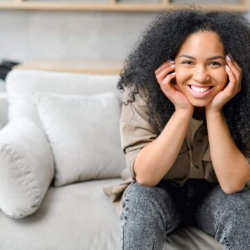 A cute black woman with wavy hair showing off her natural curl pattern after using the finger comb method.