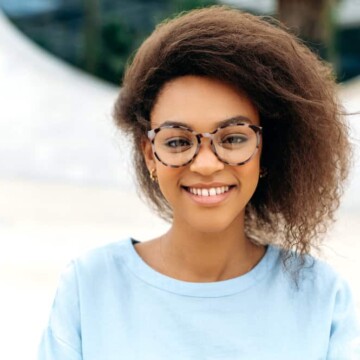 A beautiful black girl with stringy hair strands that have been cleaned with dry shampoo and styled with natural oils.