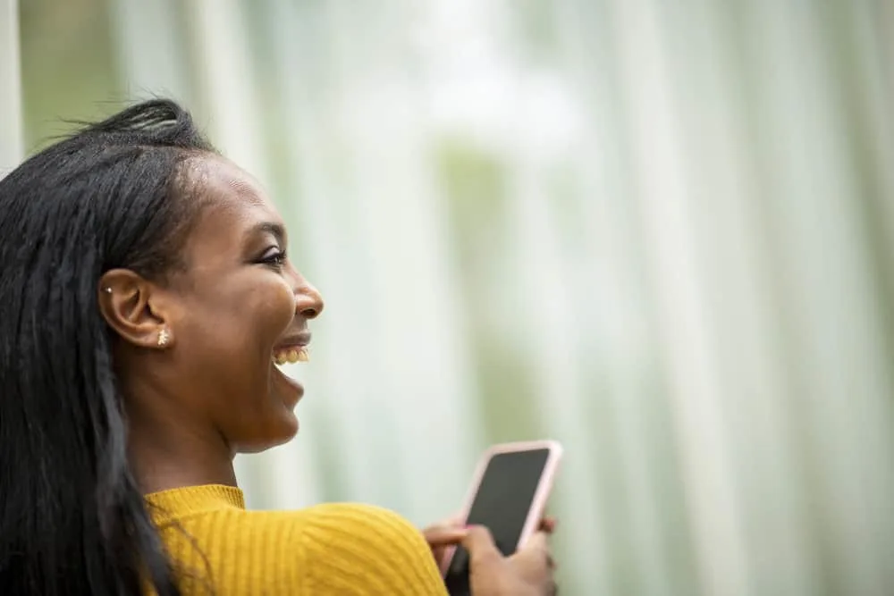 Over-the-shoulder photo of a black woman that's researching a curly hair cut that's perfect if she goes natural.