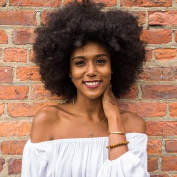 A black female with natural hair strands in a wash-and-go style highlighting her curl pattern and wiry textured hair.