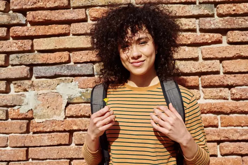 A cheerful African American female with clean hair that was washed with the perfect clarifying shampoo.