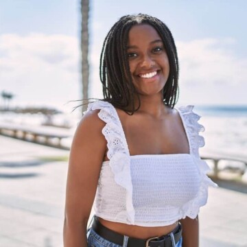 A young black girl with round facial features is wearing her versatile black hair in a cute braided hairstyle.