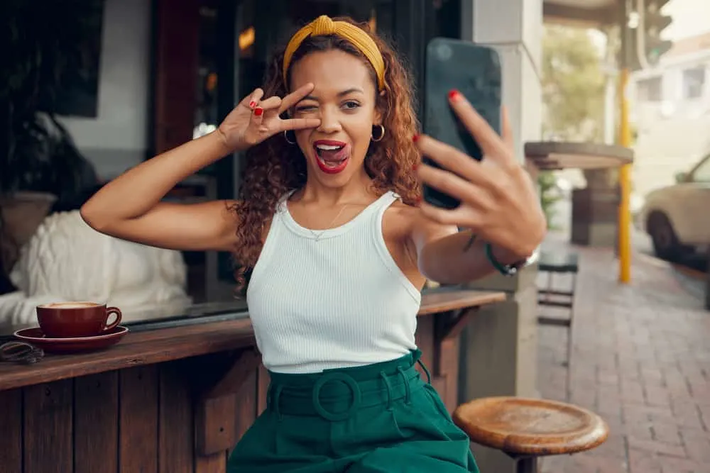 A beautiful black girl takes a selfie after washing her hair with a clarifying shampoo and styling it with essential oils.