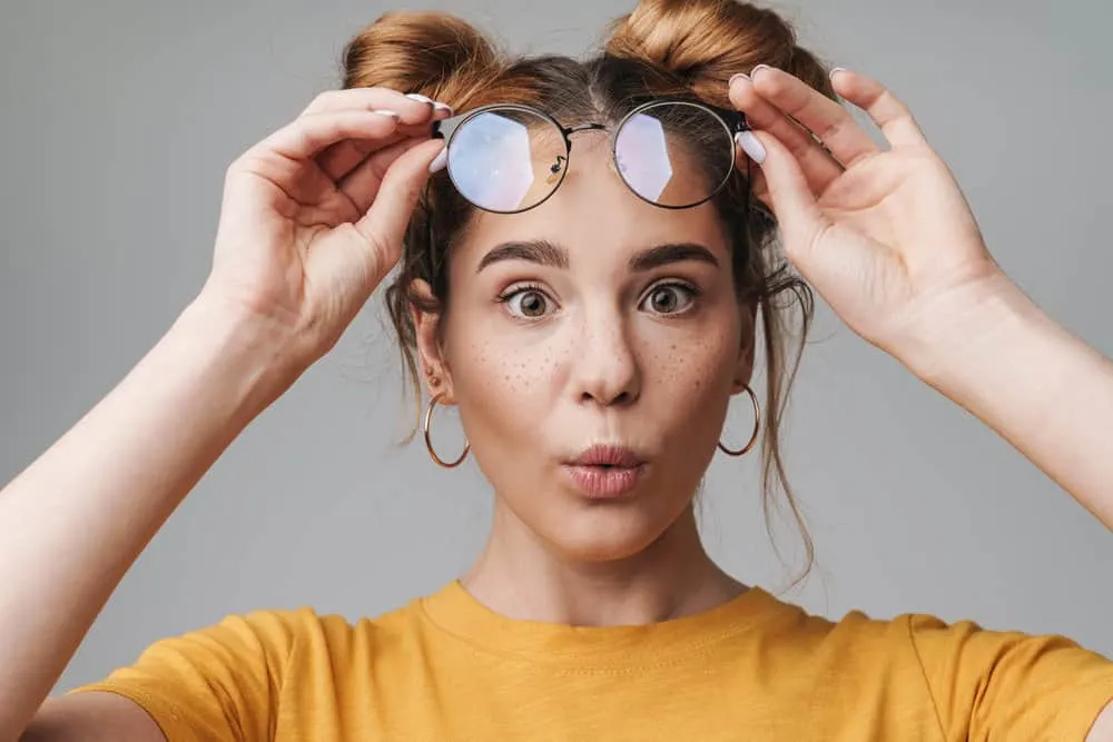 A cute young female, after air-drying her wet hair, is wearing two mini-buns on her fine hair strands.