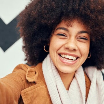 A black female with frizzy curls and wavy hair styled with flaxseed hair gel and coconut oil.