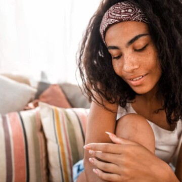 A light-skinned black girl with a type 4 hair type and dark brown hair color with a greenish tint.