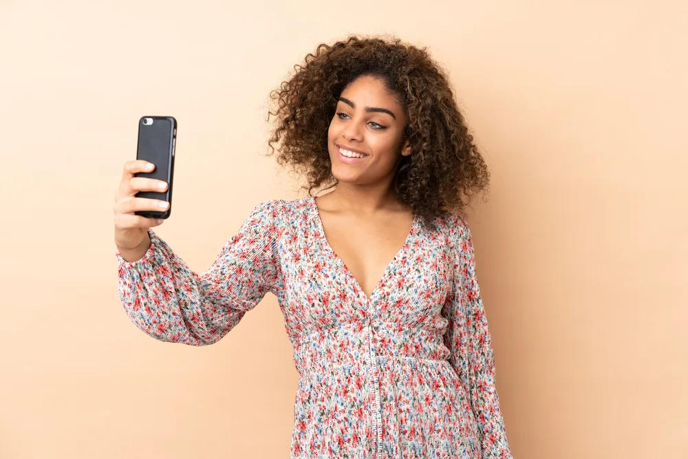 A cute black girl takes a selfie after using Geranium flower extract on her 3B hair texture.