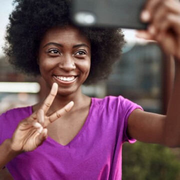 A black woman takes a selfie after stretching hair and styling her curls with coconut oil and coconut milk.