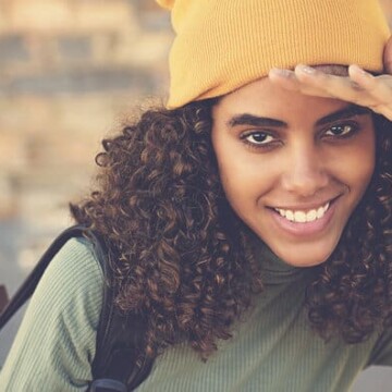 A cute black lady with healthy hair used a detangling brush to remove single-strand knots.