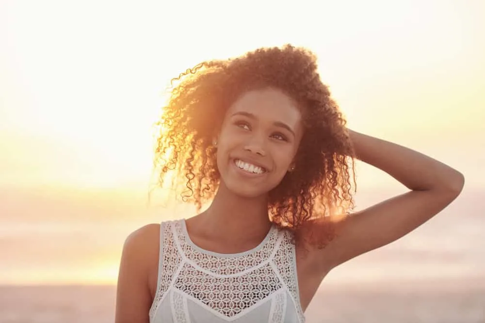 A young black girl, after removing her curly hair extensions, is pleased with her new hair growth.