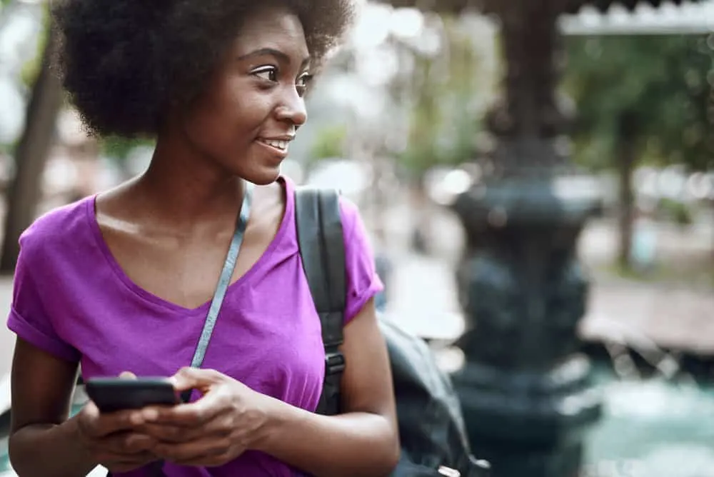 A pretty African American female with coily hair wearing her curls in a stretched-out look.