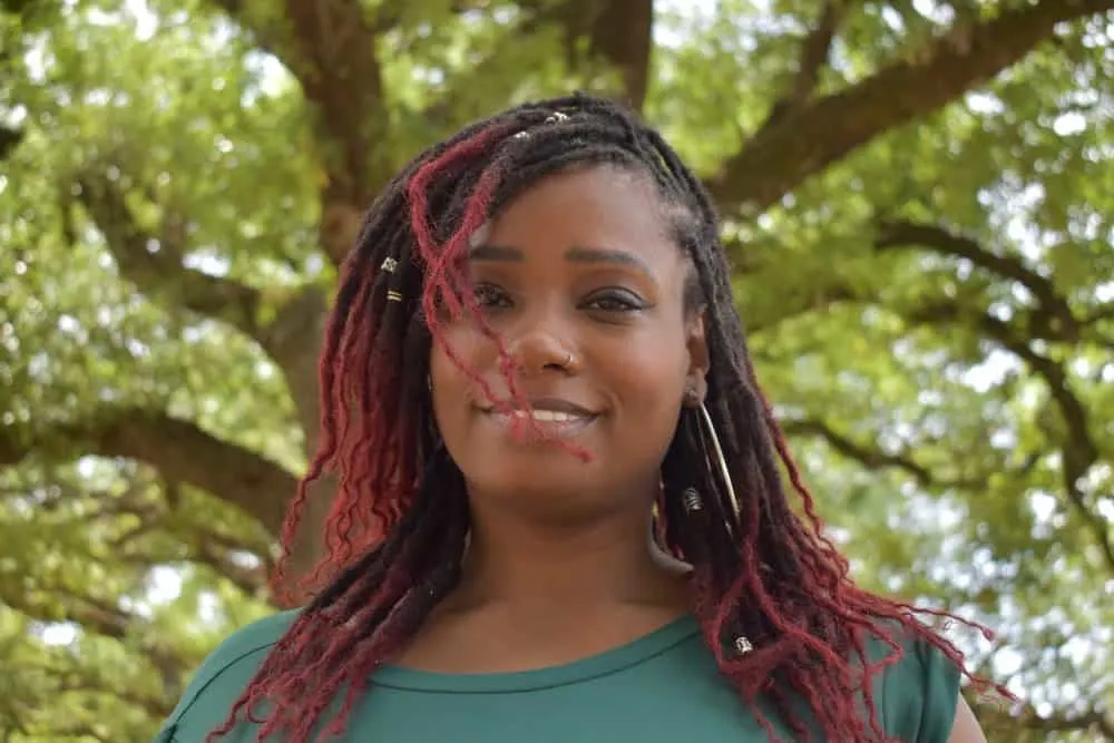 Her long, wavy hair is beautifully transformed with burgundy butterfly locs, a trendy and protective style that gives her a boho chic vibe.