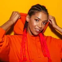 A gorgeous African American lady wearing cornrows or boxer braids with reddish hair extensions on a type 3 natural hair texture.