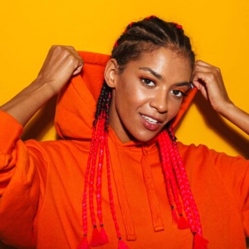 A gorgeous African American lady wearing cornrows or boxer braids with reddish hair extensions on a type 3 natural hair texture.