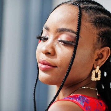 A cute black woman wearing her hair braided in a tight style with synthetic hair making her hair and scalp feel tender from the tight cornrows.