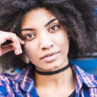 A beautiful black woman with natural curls after brushing curly hair with a Tangle Teezer to detangle her dry curly hair strands and highlight her loose curls.