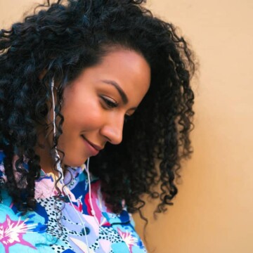 A beautiful black lady with fine hair wearing beachy waves created with a curling wand and paddle brush on her naturally coarse hair strands.