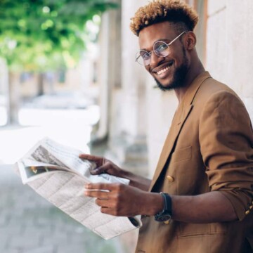 A young black man with bleached hair tips on naturally dark brown hair strands with a type 4 hair texture.