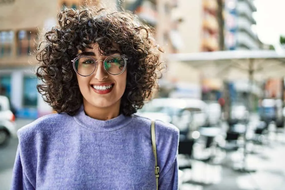 A female's hair is styled with a curling iron, showcasing the uneven distribution of hair follicles and the curl pattern that is created from a straight hair shaft.