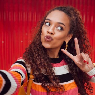 A fashionable young black girl wearing her naturally straight hair curly after using sea salt spray and natural oils on her soaking wet hair strands to create defined curls.