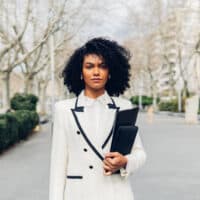 A black businesswoman with naturally curly hair has a type 3 natural curl pattern cleaned with a curly hair shampoo and styled with curl cream.