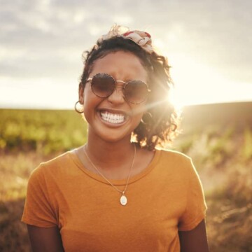 A black woman with beautiful skin that uses organic skin and haircare products with fatty alcohols and emollient properties.