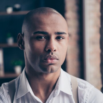 A confident black guy with sensitive skin and razor bumps used a top-rated professional hair clipper with quality blades and blade oil to avoid skin irritation.