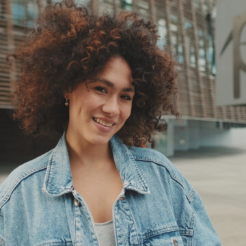 A cute young black girl wearing her natural curly pattern on type 3 natural hair that's styled with a combination of shea butter with rice amino acids and natural oils.