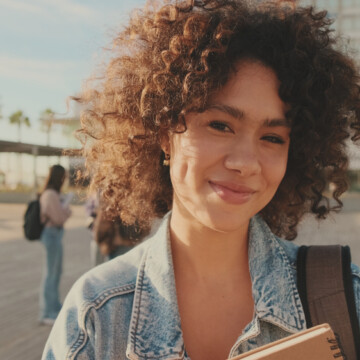 A beautiful young black girl wearing dark brown heat-free hair with natural curls enhanced by using curly hair extension wefts made from Remy human hair.