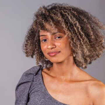 A cute black girl with oily hair used an organic shampoo and conditioner treatment before styling her natural hair strands with a natural bristle brush.