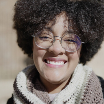 A young black female with a looser hair texture wearing a curly hairdo that was styled with whipped shea butter, coconut hair, and organic gel hair products.