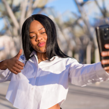 A young African American woman wearing a synthetic hair wig made with body wave hairpieces and hair extensions.