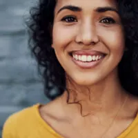 An attractive young woman standing outside after drying her soaking wet hair with a hair dryer and styling her low porosity hair strands with hair gel and shea butter.