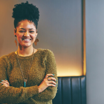 An attractive young woman with thick hair used coconut and moisture to wet hair before putting it into a pineapple style with thickening mousse that highlights her natural hair texture.