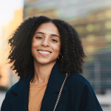 A black woman with a visible curl pattern on naturally kinky hair strands styled with organic styling creams and a leave-in conditioner.