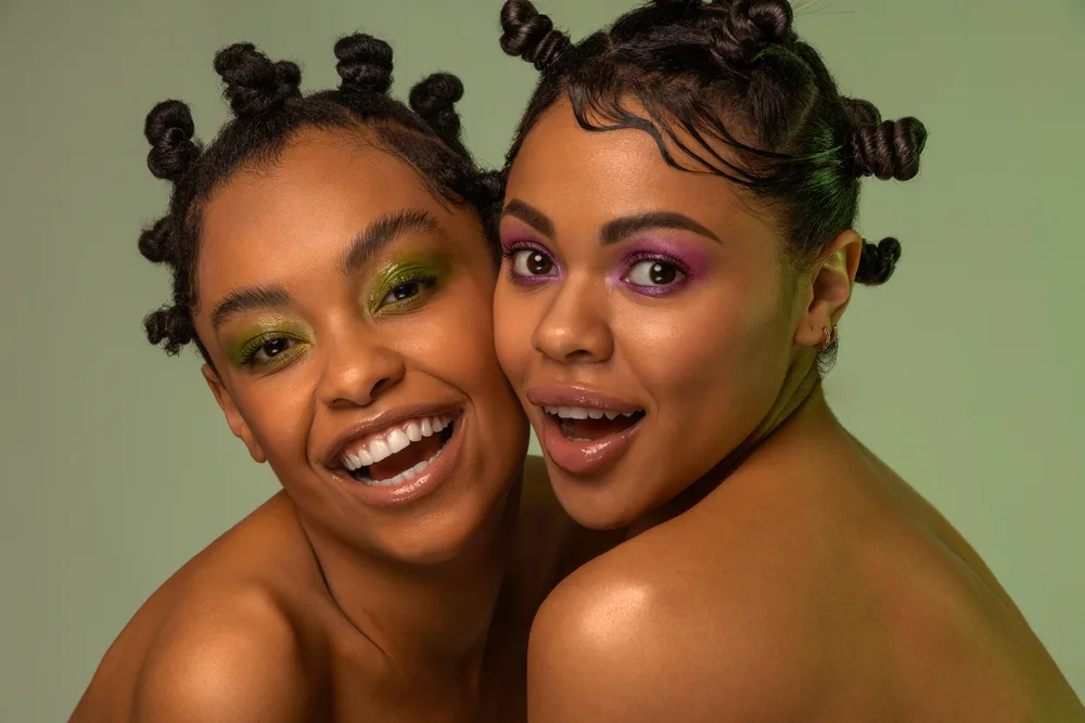 Two black ladies are preparing for the daily upkeep of Bantu knots, which involves protecting them with a silk scarf.