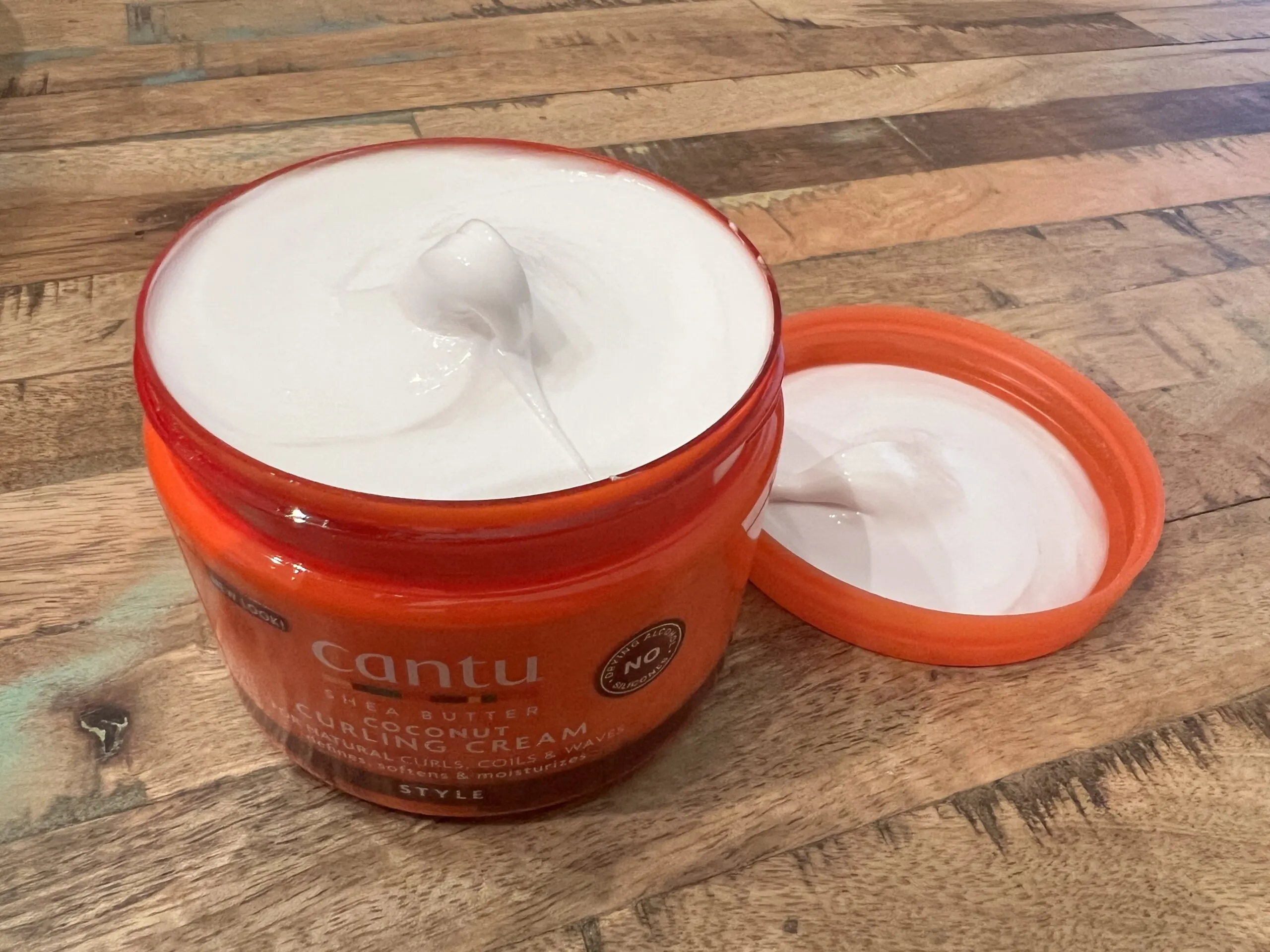 Close-up view of the creamy texture of Cantu Coconut Curling Cream, emphasizing its richness for hair care.